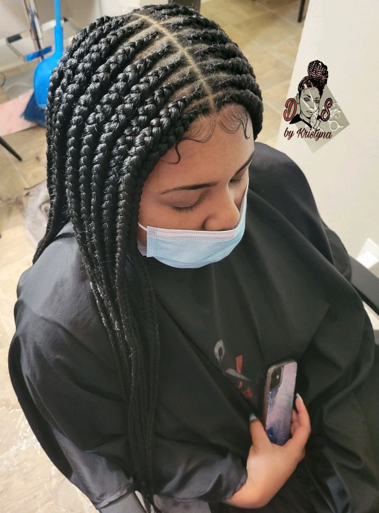 Tribal braids in black with neat straight-back rows, top view of a client in the salon chair